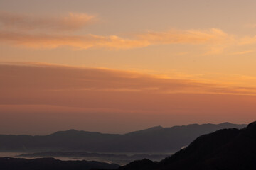 Obraz premium 埼玉県秩父市の三峰神社から望む朝焼けの山並みと空の風景。2022年11月19日撮影。晩秋の澄んだ空気の中、赤く染まった空と重なる山々が幻想的な絶景を描き、旅行や自然風景、癒しをテーマに最適です。