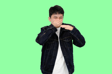 young asian man smell something bad in green isolated background