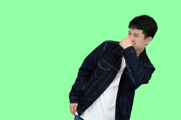 young asian man smell something bad in green isolated background