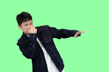 young asian man smell something bad in green isolated background
