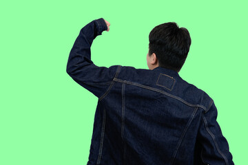 young asian man raised fist pose with victory in green isolated background