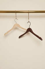 Two brown hangers on golden rod against off-white background