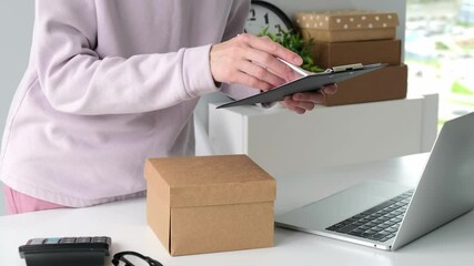 Startup small business SME, Entrepreneur owner woman using smartphone or tablet taking receive and checking online purchase shopping order to preparing pack product box. - Powered by Adobe