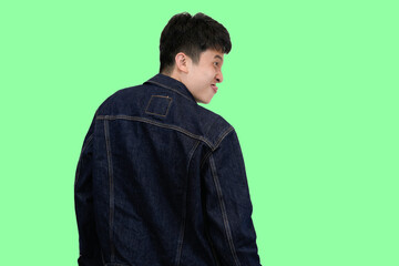 young asian man turned away with funny pose in isolated green background