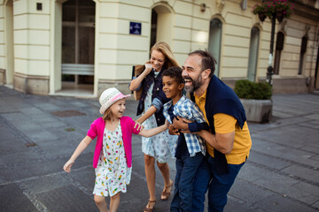 Happy multicultural family with kids walking together on city street