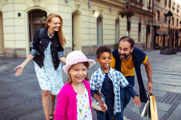 Happy multicultural family with kids walking together on city street