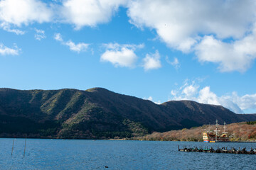 神奈川県箱根町の観光名所、芦ノ湖に浮かぶ海賊船（遊覧船）。冬の青空と雄大な山々を背景に、港に停泊するカラフルな船。箱根の観光や旅行、休日のレジャーをテーマにした、楽しく美しい風景。

