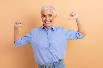 Confident mature woman gestures enthusiastically with a bright smile against a neutral beige...
