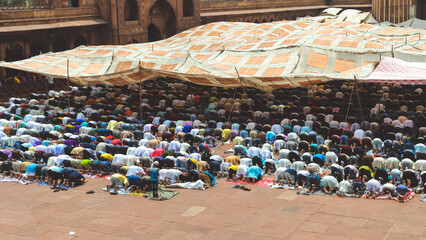 Muslim men and children bowing down and offering Namaz prayers on the occasion of Eid'Al-Fitr at the famous Jama Masjid in Old Delhi, India. They are dressed in festive kurta pyjamas and skullcaps