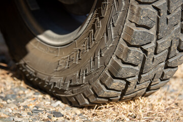 アウトドアやオフロード走行に適した4WD車のタイヤを接地面からクローズアップ撮影。深いトレッドパターンが特徴的なSUV用オールテレーンタイヤで、悪路や砂利道、林道など様々な路面環境に対応。アウトドアやキャンプ、車中泊、車旅などのテーマにも利用可能な自動車部品の詳細写真。

