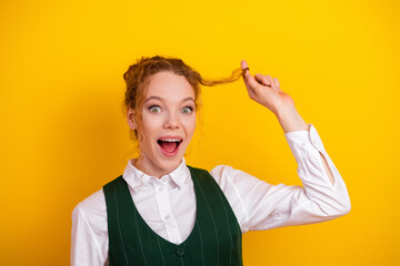 Excited young student with red hair and waistcoat making joyful gestures on a vibrant yellow...