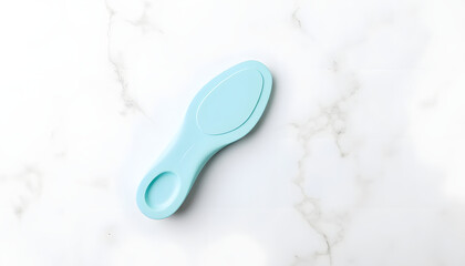 Light blue ergonomic tool designed for personal care, resting on a smooth marble surface, showcasing its sleek design and functionality for everyday grooming tasks