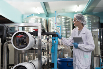 Drinking water manufacturers and production line. Water filter machine. Female worker inspecting...