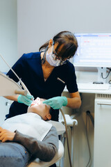 A woman dentist treats a patient's teeth in a dentistry home.