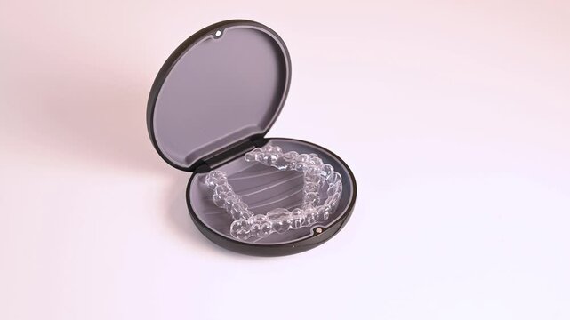 Invisible orthodontic braces in case rotating on white background