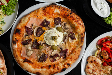 Table scene with a variety of delicious foods. Angled and perspective View over a dark wood background.
