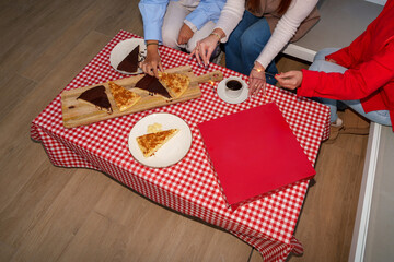 Friends celebrating with cake slices, sparklers, coffee mug, red gift box on checkered tablecloth, sharing joyful moment together