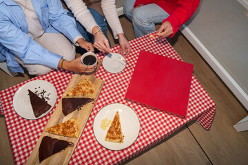 Celebrating friendship, friends enjoying sparklers, coffee, cake slices, red gift box on checkered tablecloth