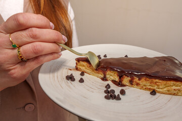 Pastry professional savoring chocolate cake garnished with cocoa chips, golden utensil in hand