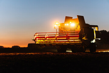 Combine harvester harvesting wheat at sunset