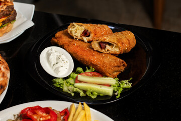 Table scene with a variety of delicious foods. Angled and perspective View over a dark wood background.