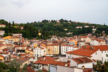 charming coastal town with red rooftops and colorful buildings surrounded by lush green hills. Piran old town, Slovenia 