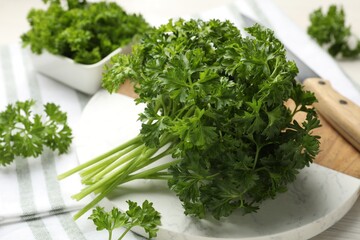 Fresh parsley and knife on light wooden table, closeup