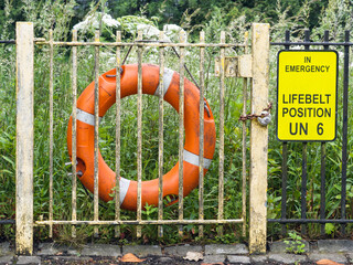Red buoy life safety ring on fence at riverbank in Glasgow