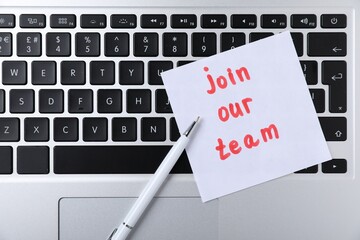 Paper note with words Join Our Team and pen on laptop, top view