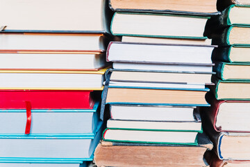 Stacks of old books arranged with page edges facing the camera. Neutral background, vintage feel,...