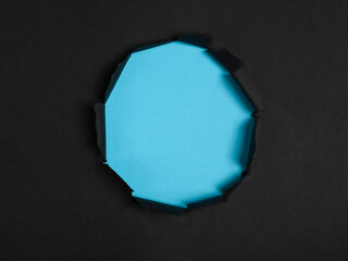 Tear hole in center of black paper reveals cyan background