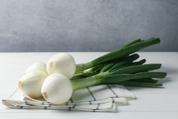 Fresh ripe green onions and towel on white wooden table. Space for text