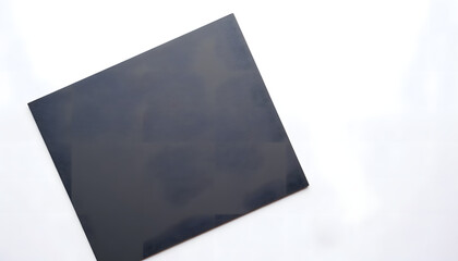 Blank black square paper mock up with copy space for design, showcasing a smooth texture on a minimalistic white background for creative projects and presentations
