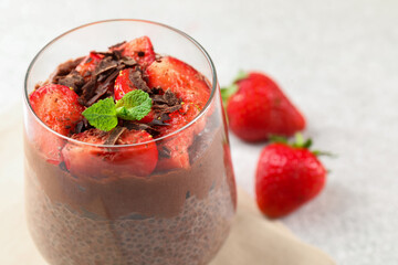 Delicious chocolate pudding with chia seeds, strawberries and mint on table, closeup. Space for text