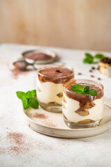 Traditional Italian dessert tiramisu in a glass on light background
