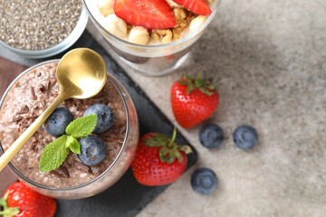 Delicious chocolate pudding with chia seeds, strawberries and blueberries in glass on light grey...