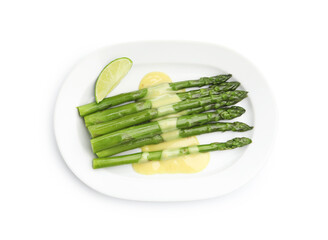 Tasty cooked asparagus with sauce and lime isolated on white, top view