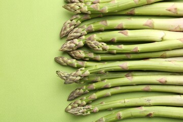 Fresh ripe raw asparagus on green background, closeup