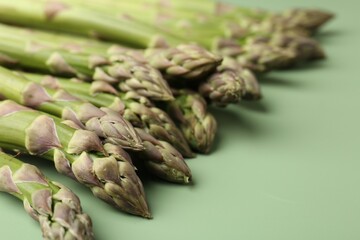 Fresh ripe raw asparagus on green background, closeup