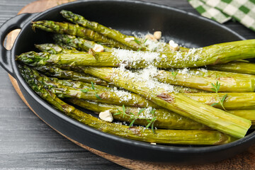 Tasty cooked asparagus served with parmesan on black wooden table, closeup