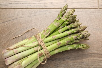 Fresh raw asparagus spears on wooden table, top view