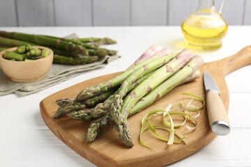 Fresh raw asparagus spears and knife on white wooden table, closeup