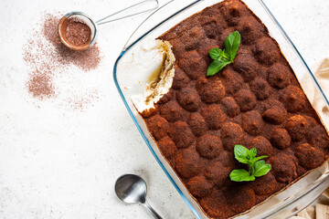 Traditional Italian dessert tiramisu in a glass backing form on light background, top view