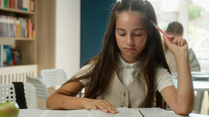 Pensive concentrated student Caucasian little girl schoolgirl pupil learner nerd read book library...