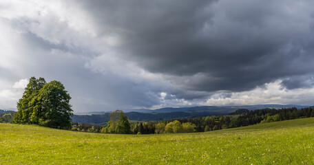 Dark clouds gathering over a green meadow and hills landscape
