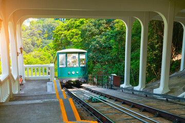 The famous green tram passes the intermediate station before the peak on the slope of Victoria in...