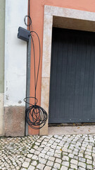 Tangled black cables dance like urban vines against rustic backdrop, whispering secrets of...