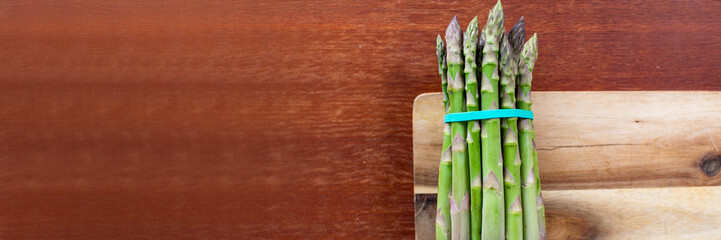Vibrant asparagus spears bundled on rustic board, evoking Ostara renewal, gourmet charm, and...