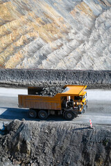 Yellow dump truck braves the labyrinthine quarry, evoking industrial strength, Earth Day...