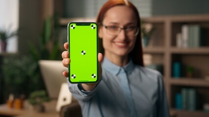 Caucasian smiling woman happy business girl businesswoman buyer shopper customer user in office holding mobile phone green screen chroma key empty mockup copy space smartphone app online shopping ads